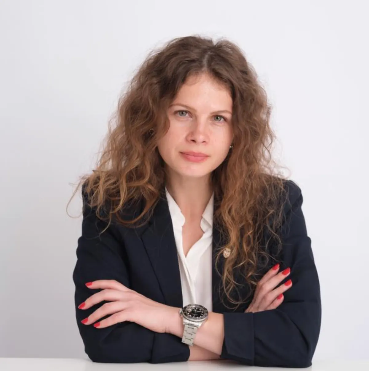 Roxana Cantea, cu brațele încrucișate, în sacou negru, pe fundal alb